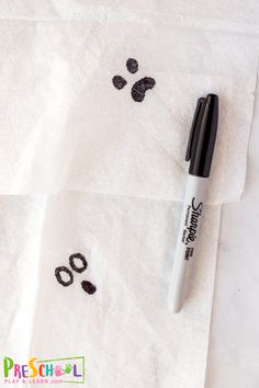 a pen sitting on top of a white towel next to a pair of paw prints