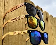 three pairs of sunglasses with the names grooms and best man on them hanging from a wooden fence