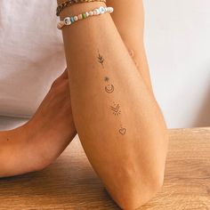 a woman's arm with tattoos on it sitting on top of a wooden table