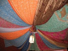 the inside of an umbrella with many different colored fabrics hanging from it's sides