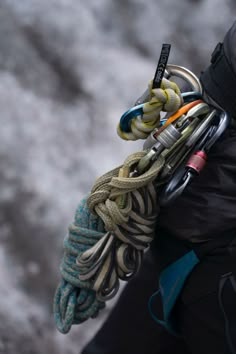 there is a man holding several different items in his hand and climbing gear attached to him