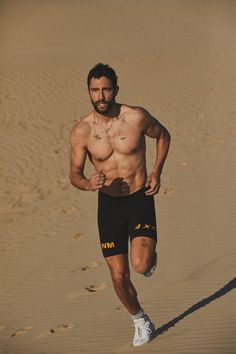 a man running in the sand with no shirt on