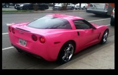 a pink car is parked on the side of the road