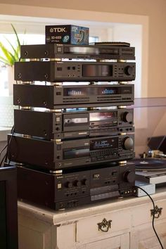 a stack of stereo equipment sitting on top of a dresser