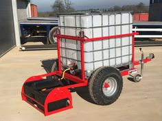 a red and white trailer with a large container on it's front wheel, attached to a forklift