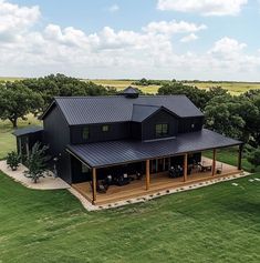 an aerial view of a large black house in the middle of a green field with trees