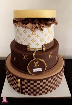 three tiered cake decorated with louis vuitton patterns and gold trimmings