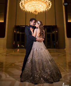 a bride and groom standing in front of a chandelier at their wedding reception