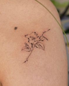 a small flower tattoo on the back of a woman's left shoulder and arm