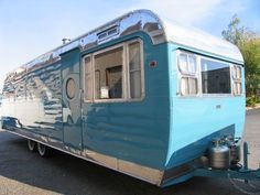 an old blue trailer parked in a parking lot