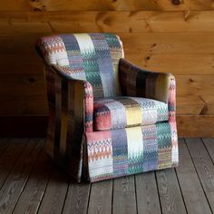 a multicolored chair sitting on top of a wooden floor next to a wall