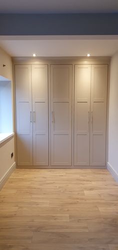 an empty room with wooden floors and white cupboards on either side of the wall