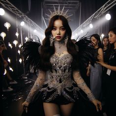 a woman in a costume with wings and jewels on her head standing next to other women