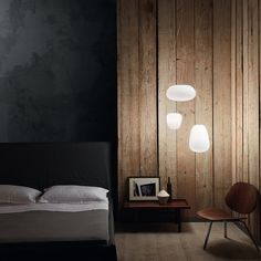 a bed sitting next to a wooden wall with three lamps on it's sides