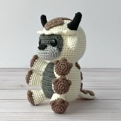 a crocheted stuffed animal sitting on top of a wooden table next to a white wall