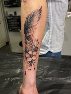 a person with a feather and flower tattoo on their leg