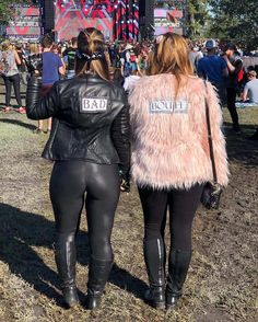 two women in black leather pants and jackets walking towards a stage