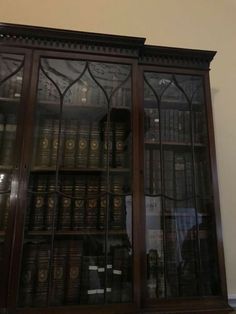 an old wooden bookcase with many books on it's glass doors and shelves