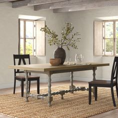 a dining room table with chairs and a vase filled with flowers on top of it