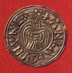 an ancient coin is shown on a red surface