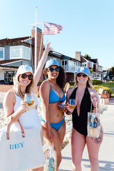 three beautiful women in bikinis holding up beers