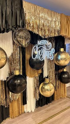 christmas decorations hanging from the side of a wall in front of a window with gold and black curtains