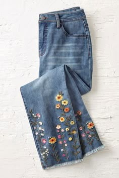 a pair of jeans with embroidered flowers on them