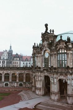 an old building with a clock on it's face in the middle of a courtyard