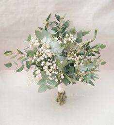 a bouquet of white flowers and greenery on a white tableclothed background with copy space