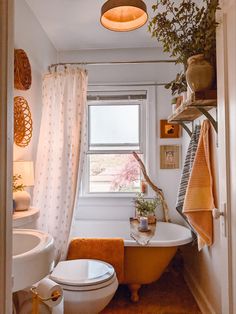 a bathroom with a tub, toilet and sink in it next to a potted plant