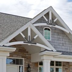 the front entrance to a house with white trim and stonework on the roof, along with two large windows