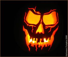 a pumpkin carved to look like a skull with glowing eyes and mouth, in the dark