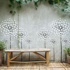 a bench sitting in front of a wall with dandelions painted on it