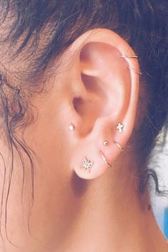 a woman's ear with three piercings on top of her head and one behind the ear