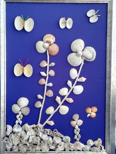 sea shells and flowers are displayed in a silver frame on a blue background with butterflies