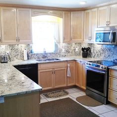 a kitchen with marble counter tops and stainless steel stove top oven, dishwasher, microwave and refrigerator