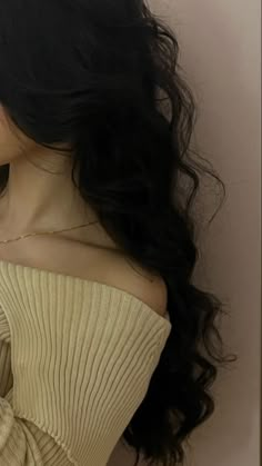 a woman with long black hair wearing a tan sweater