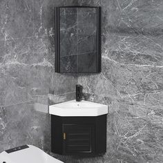 a white toilet sitting next to a black sink in a bathroom under a framed mirror