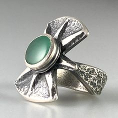 "Chrysoprase Tufa Cast Silver Ring Tufa cast silver ring with gem quality Chrysoprase and carved design this combination of traditional primitive techniques along with contemporary sculpting and simple strong lines makes timeless statement. This is a true one-of-a-kind statement ring of heavy silver and striking design. Measurements: Ring Fits approximate size 9 3/4 The top with the chrysoprase measures 1 1/8\" x 1\".  Band Measures approximate 3/8\" at the widest point and is tapered to approxi Polished Chrysoprase Ring Jewelry, Contemporary Green Sterling Silver Jewelry, Artisan Hand Forged Green Rings, Silver Chrysoprase Cabochon Emerald Ring, Modern Green Chrysoprase Jewelry, Tufa Casting, Ring Sale, Jewelry Studio, Ring Fit