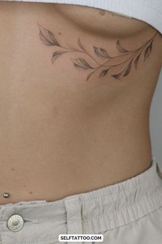 a woman's lower back tattoo with leaves on her left side ribcage