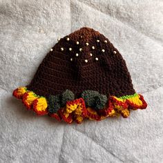 a crocheted hat with flowers on it sitting on top of a white blanket