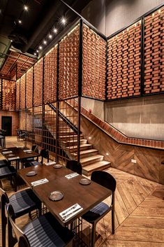 an empty restaurant with wooden tables and chairs next to the stairs that lead up to the second floor