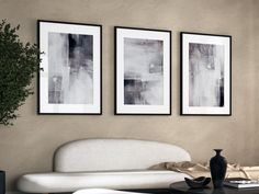 three framed pictures hang on the wall above a white couch and coffee table in a living room