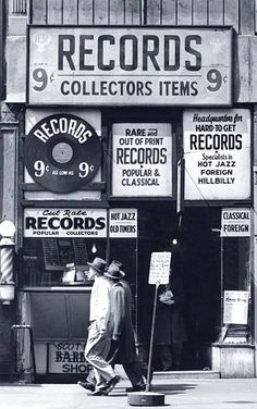 a man walking past a record store with records on the front