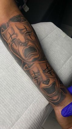 a man with a tattoo on his arm has a face and cross in the middle