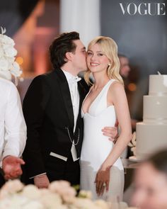 a man and woman kissing in front of a wedding cake