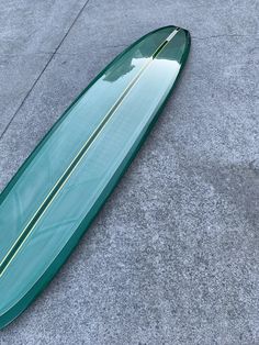 a green surfboard laying on the ground in front of a concrete flooring area