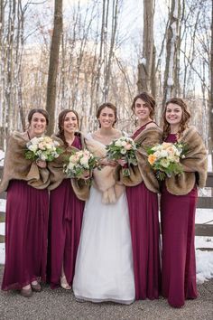 the bride and her bridesmaids are dressed in burgundy dresses with fur stoles