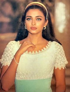 an old photo of a woman with long hair wearing a white top and green skirt