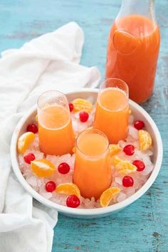 three glasses of orange juice on a plate with ice